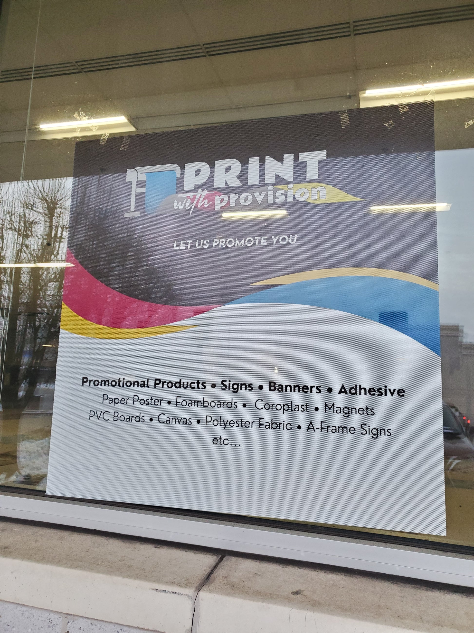 Custom perforated window film with Print With Provision branding, installed on storefront window for advertising and promotional display.