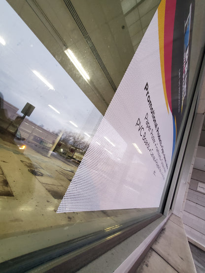 Print With Provision custom perforated window film installed on storefront glass, exterior side angle view showing see-through vinyl for promotional advertising.