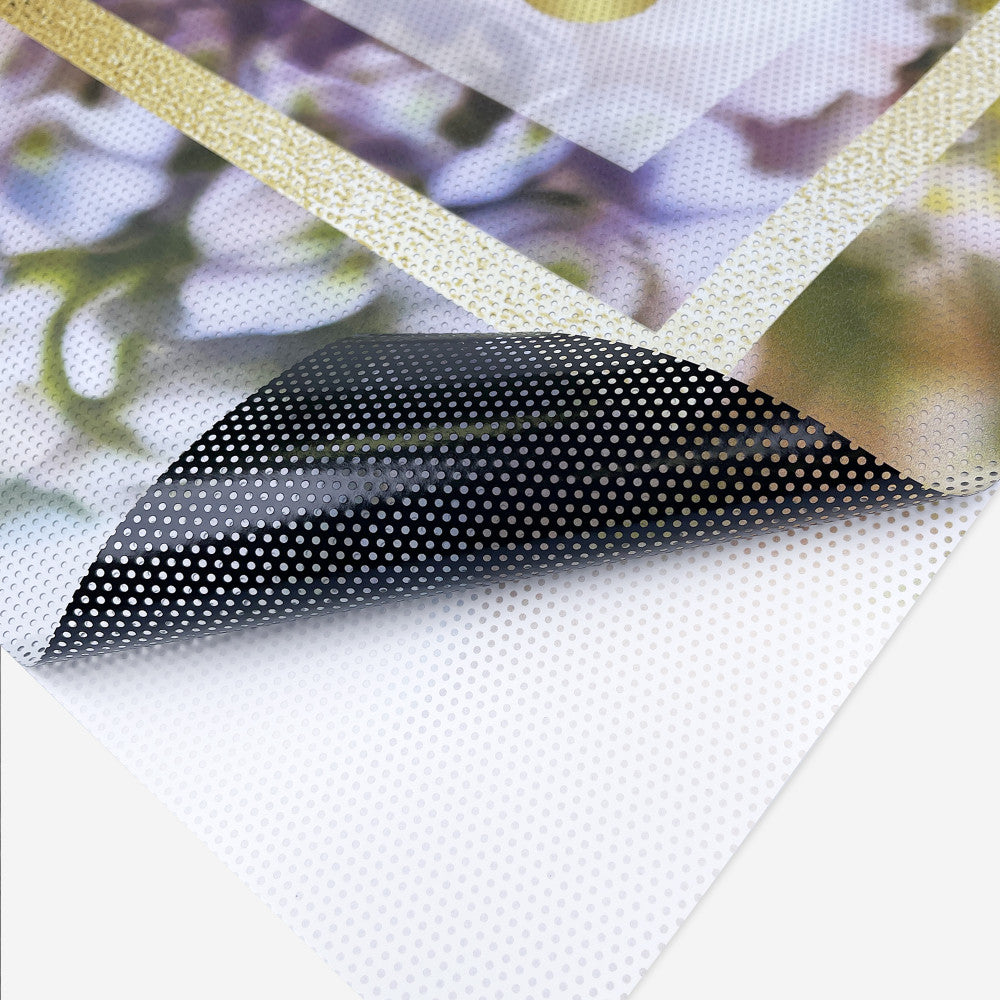 Close-up of custom printed perforated window film with adhesive backing, showing see-through vinyl material for storefronts and vehicle windows.